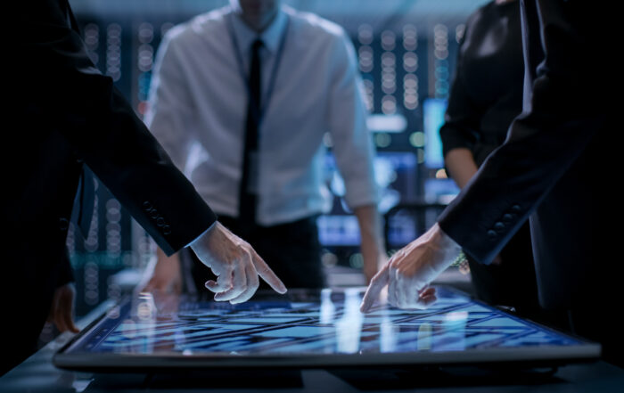 Business professionals engaged in corporate decision making, analyzing data on a digital touchscreen in a modern office setting.