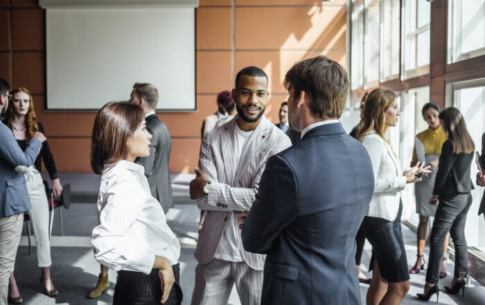 People networking at a professional event representing small business owner peer groups, discussing growth strategies and business insights.